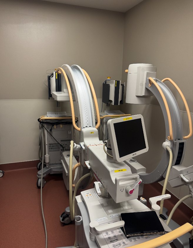 Mobile C-arm positioned beside an operating table in a surgical suite