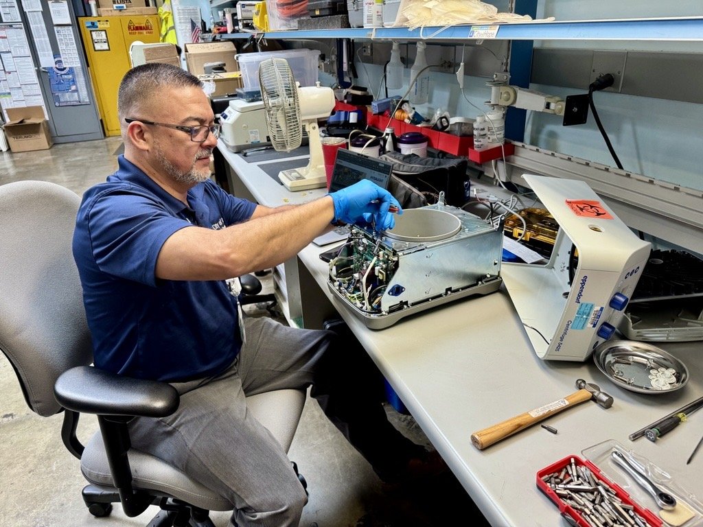 Technician servicing surgical imaging equipment on a bench